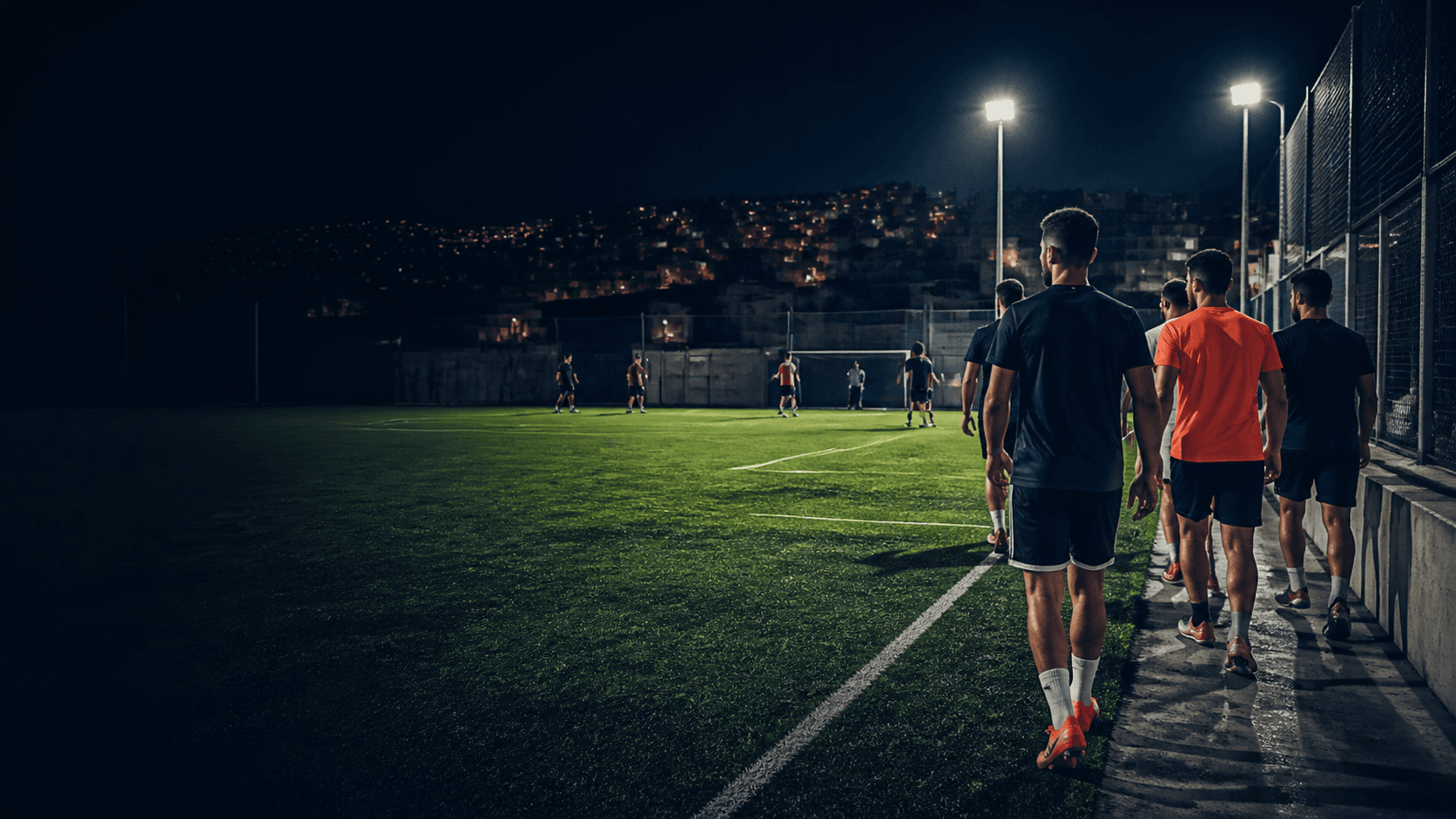 Players walking onto a football pitch at night in Amman